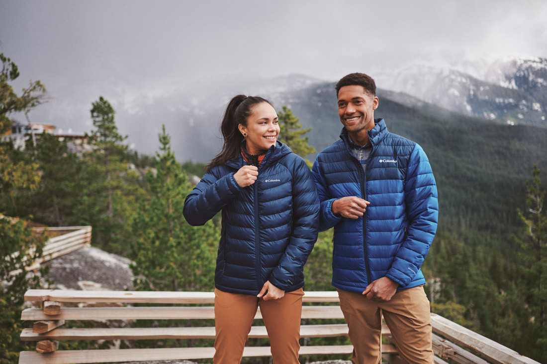 a couple wears matching columbia jackets on a wintery mountain