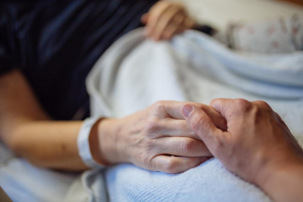 Holding hands on hospital bed.