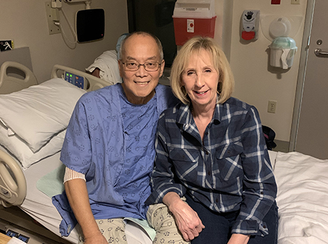 Peter and his wife sitting and smiling on his hospital bed