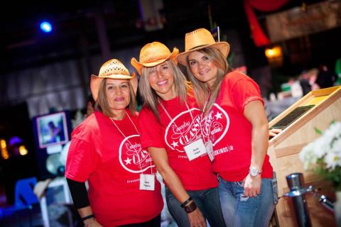 three ladies wearing cowboy hats volunteering at country classic auction