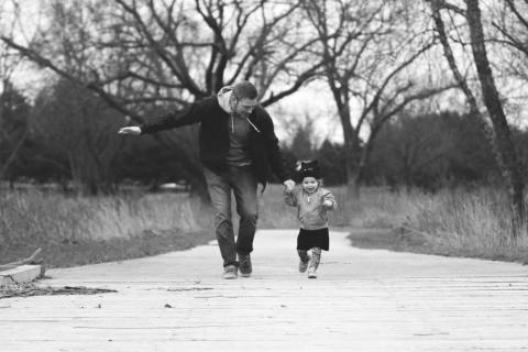 A father walks hand-in-hand with his young daughter