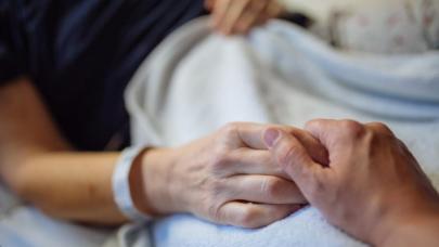 Holding hands on hospital bed.