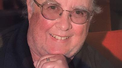 Murray Jones smiling at the camera, resting his chin on his hand.