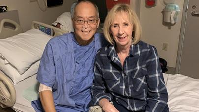 Peter and his wife sitting and smiling on his hospital bed