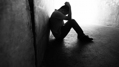 young man sits on the ground with his head in his hands